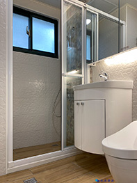 淋浴間牆面選用與鄰牆同款不同色彩壁磚做跳色，並搭配木紋地磚